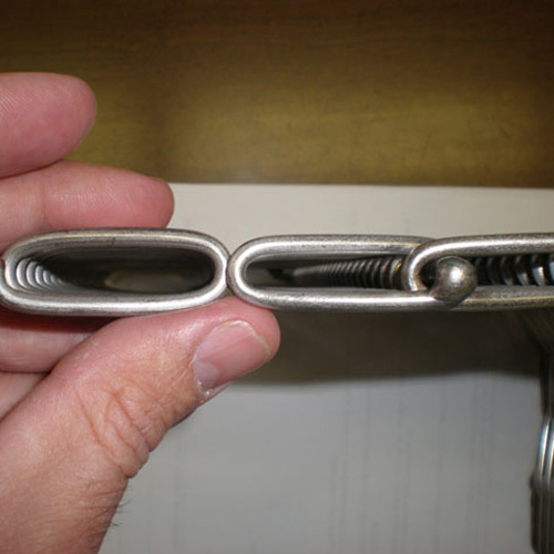 A hand holding the wire mesh spiral of a conveyor belt.