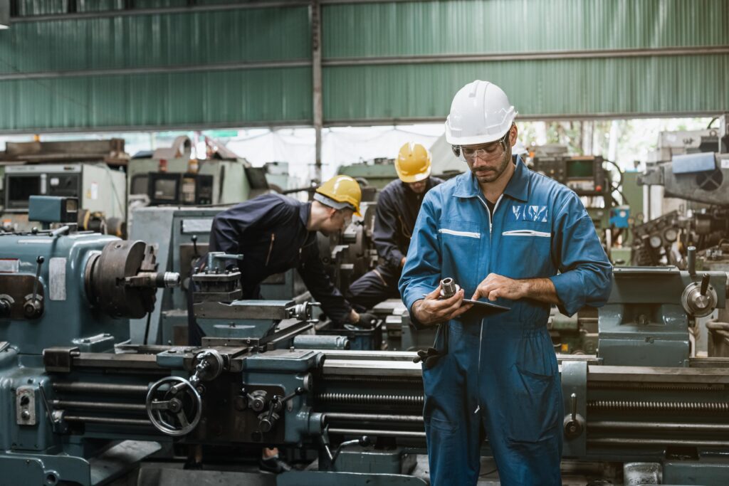 Worker in a crowded factory checking conveyor belt components.