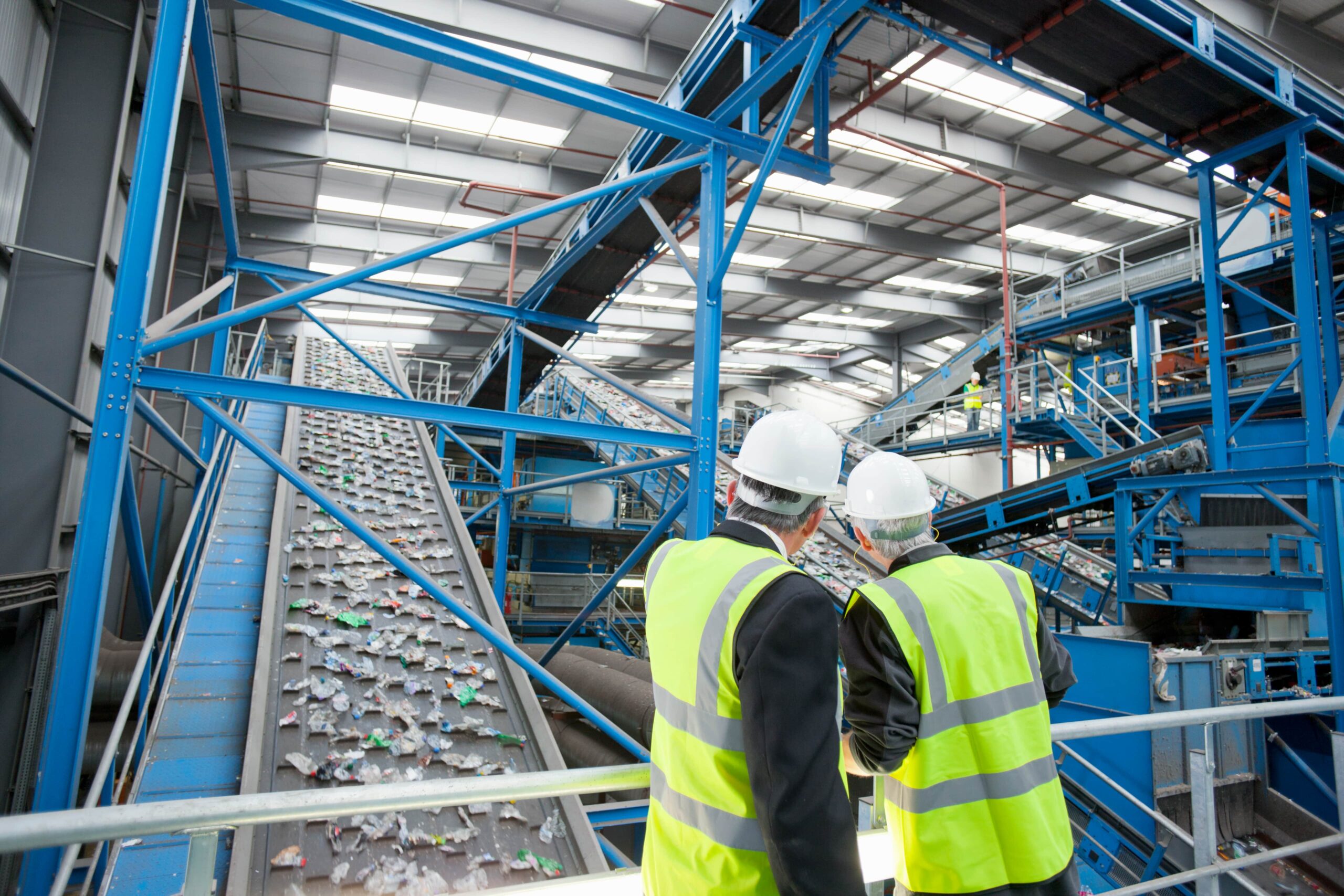 Two manufacturing workers observing conveyor belts in a factory.